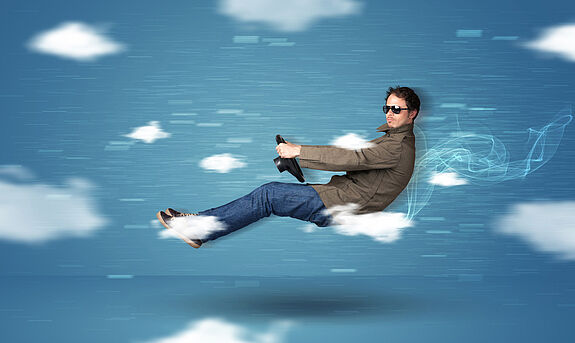 Ein Mann fährt Auto ohne Auto vor einem Wolkenbild.