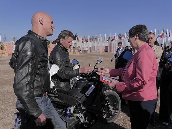 Umweltministerin Barbara Hendricks begrüßt zwei Elektromotorradfahrer nach ihrer Tour von Berlin nach Marrakesch